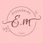 Logotipo da E.M Acessórios Finos: monograma E.M em letra cursiva vinho dentro de um círculo com ramos florais, sobre fundo rosa