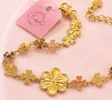 Pulseira floral da E.M banhada a ouro 18k, com flores douradas e detalhes rosados, e etiqueta da marca